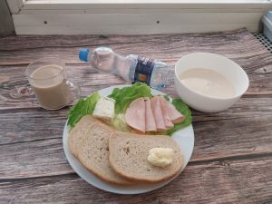 Zdjęcie przedstawia Dietę podstawową:  Kasza manna z jabłkiem prażonym Chleb mieszany pszenno-żytni Masło extra  Kawa zbożowa z mlekiem Serek Fromage  Pasta z pieczonych buraków dieta Woda mineralna n/g Szynkowa dębowa drobiowa kiełbasa grubo rozdrobniona Sałata zielona